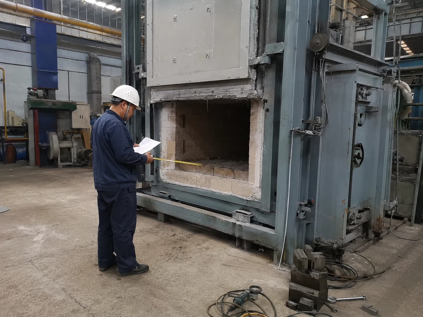 Engineer reviewing documents and the door and lining of a shut-down industrial furnace